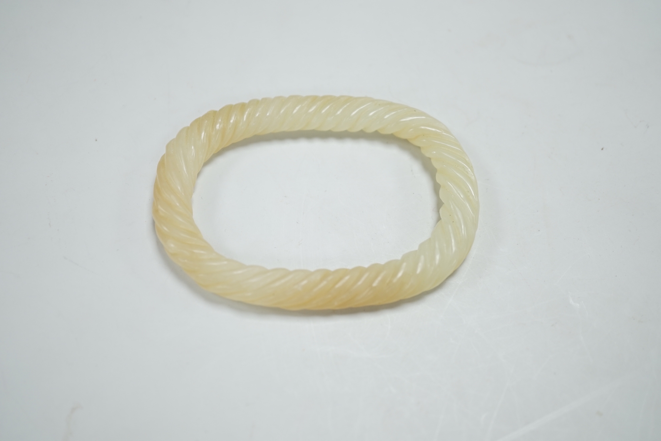 A Chinese pale celadon jade rope twist bangle, 8.3cm wide